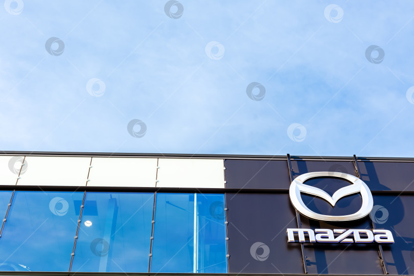Скачать Логотип бренда Mazda на фоне ярко-голубого неба фотосток Ozero