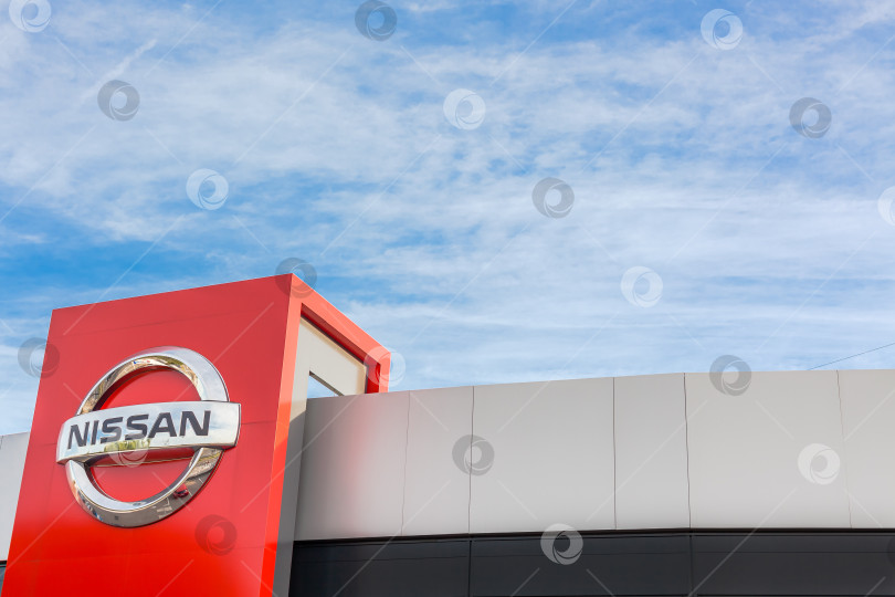 Скачать Логотип бренда Nissan на фоне ярко-голубого неба фотосток Ozero