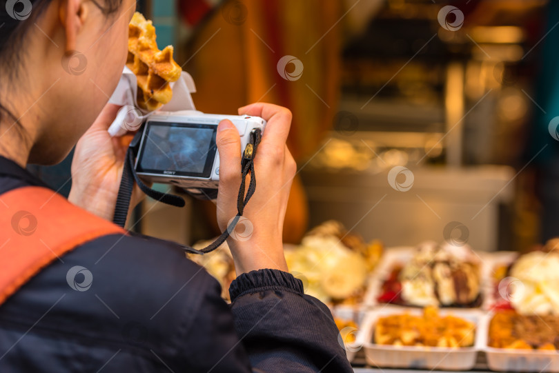 Скачать Обратная сторона фотографии молодой женщины, фотографирующей бельгийские вафли фотосток Ozero