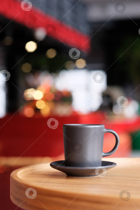 Скачать Маленькая черная кофейная чашка на блюдце на деревянном столе. Кофе в кафе на фоне размытого фона фотосток Ozero