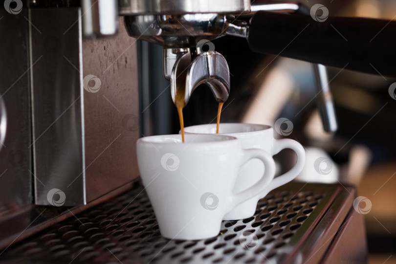 Скачать Эспрессо-машина наливает две порции кофе в белые чашки. фотосток Ozero