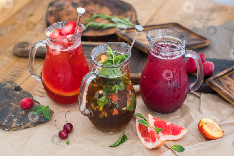 Скачать Композиция из стеклянных графинов с освежающими безалкогольными напитками, приготовленными из свежих фруктов и ягод. фотосток Ozero