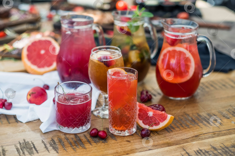 Скачать Композиция из стеклянных графинов и бокалов с освежающими безалкогольными напитками, приготовленными из фруктов и ягод. фотосток Ozero