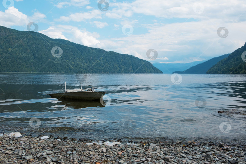 Скачать Красивый пейзаж берега озера с каменным берегом и старой лодкой фотосток Ozero