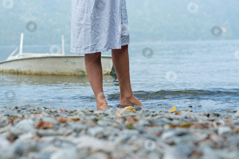 Скачать Девушка идет по каменистому берегу босиком, ее ступни в воде фотосток Ozero
