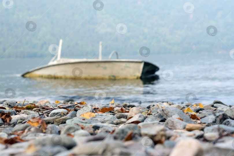 Скачать Красивый пейзаж берега озера с каменным берегом и старой лодкой фотосток Ozero