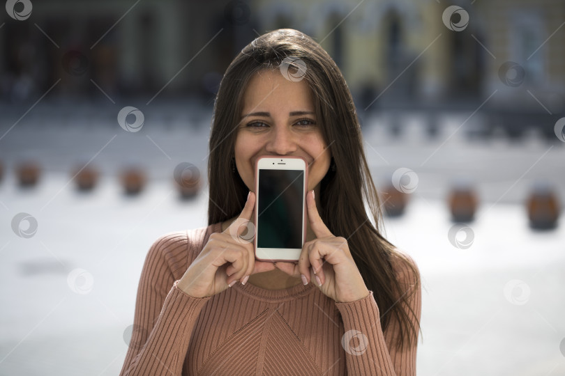 Скачать Молодая красивая девушка показывает экран своего смартфона фотосток Ozero