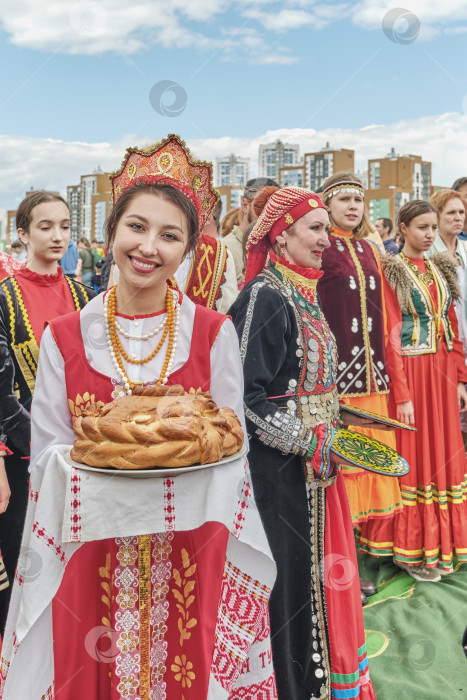 Скачать Девушка в национальной русской праздничной одежде встречает гостей праздника Сабантуй традиционным пирогом фотосток Ozero