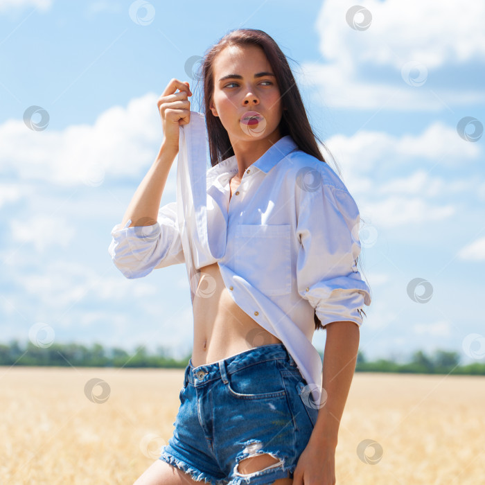 Скачать Молодая брюнетка в белой рубашке и джинсовых шортах фотосток Ozero