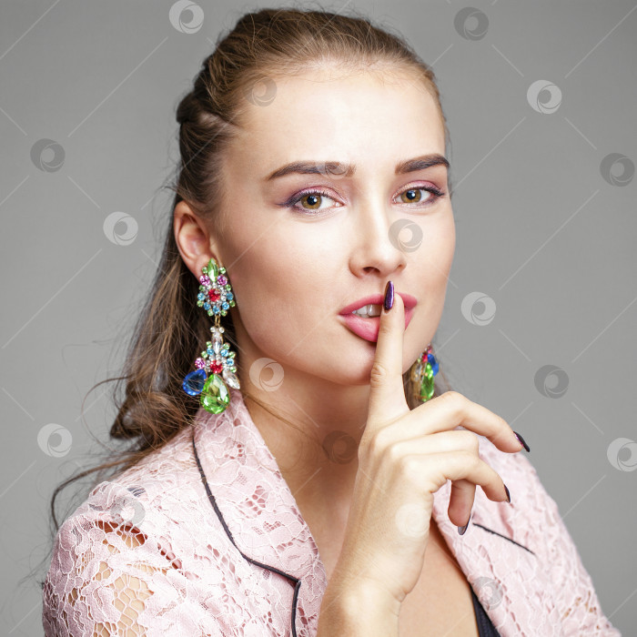 Скачать Молодая красивая блондинка приложила указательный палец к губам в знак приветствия фотосток Ozero
