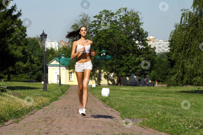 Скачать Молодая женщина бежит по летнему парку фотосток Ozero