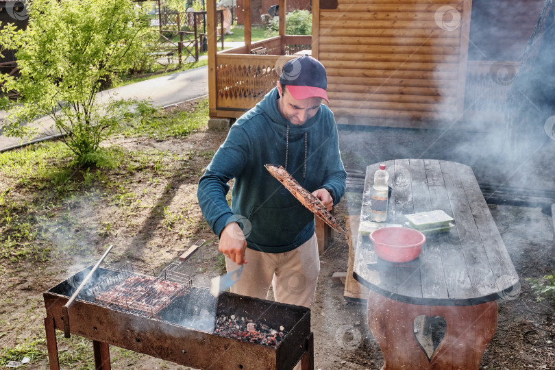 Скачать Мужчина средних лет готовит куриное мясо на гриле для барбекю на заднем дворе. фотосток Ozero