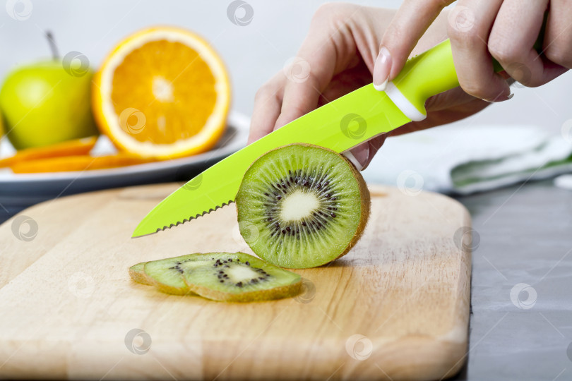 Скачать Кухонный нож для фруктов и овощей. Женские руки режут свежий киви на кухне фотосток Ozero