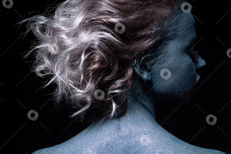 Скачать девушка с синим лицом в блестках крупным планом на фоне черной стены смотрит в камеру фотосток Ozero