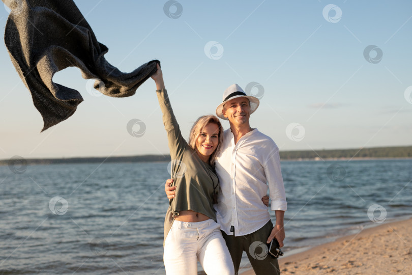 Скачать женщина и мужчина прогуливаются по пляжу на закате фотосток Ozero