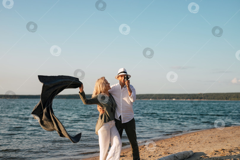 Скачать женщина и мужчина прогуливаются по пляжу на закате фотосток Ozero