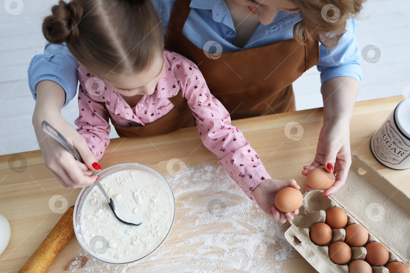 Скачать мама и ее дочь готовят на кухне из муки и яиц фотосток Ozero