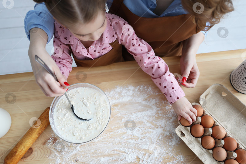 Скачать мама и ее дочь готовят на кухне из муки и яиц фотосток Ozero