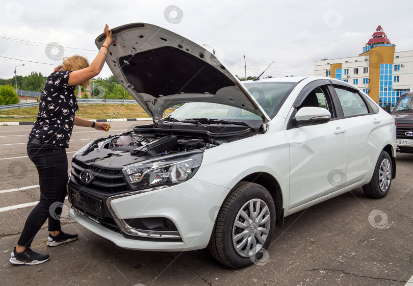 Скачать Девушка открывает капот нового автомобиля Lada Vesta фотосток Ozero