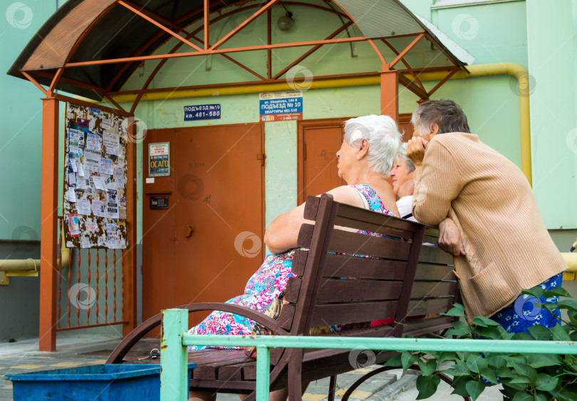 Скачать Скучающие пенсионеры сидят на скамейке у подъезда фотосток Ozero