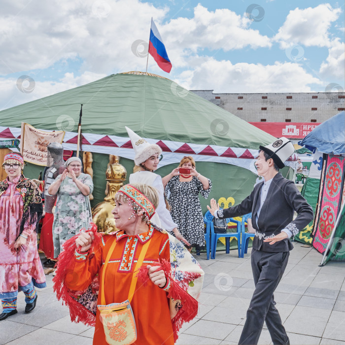 Скачать Танцует пожилая женщина в традиционной праздничной одежде народа манси. Традиционная ярмарка в Ирбите, Россия фотосток Ozero