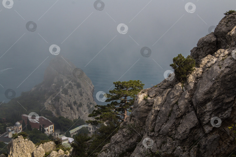 Скачать море у подножия скалы в тумане фотосток Ozero