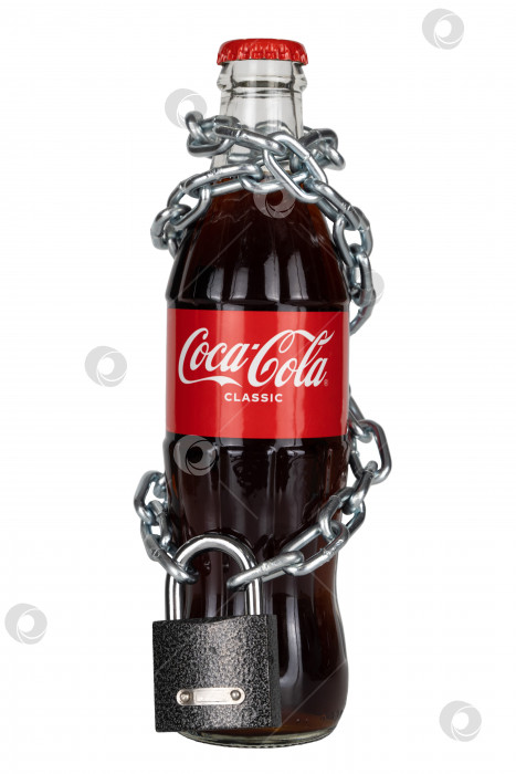 Скачать Россия, Красноярск, март 2022 года: бутылка Coca-cola, обернутая цепочкой с висячим замком. фотосток Ozero