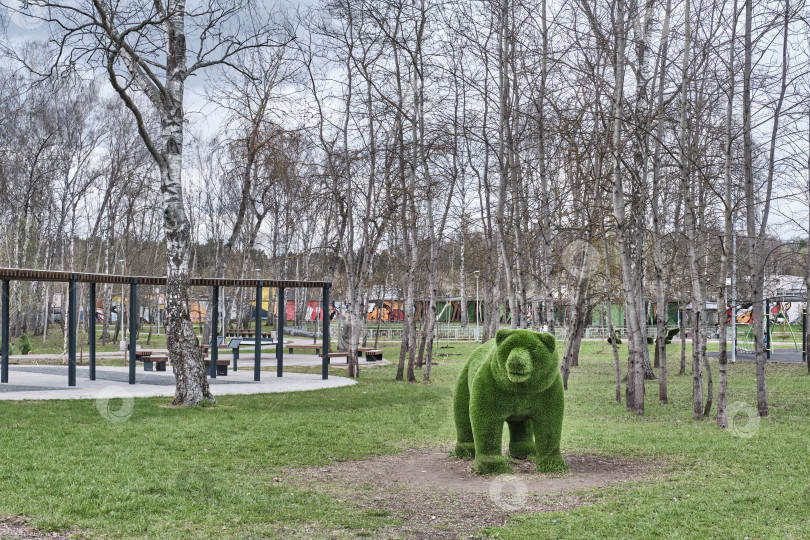 Скачать Кустовая скульптура медведя, топиарий, в весеннем городском парке фотосток Ozero