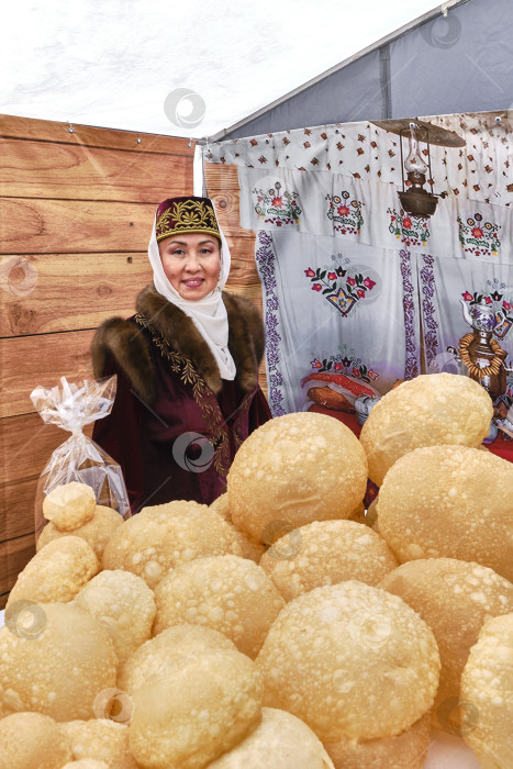 Скачать Улыбающаяся зрелая азиатка, на переднем плане традиционная выпечка баурсаки.Татарский гастрономический фестиваль фотосток Ozero