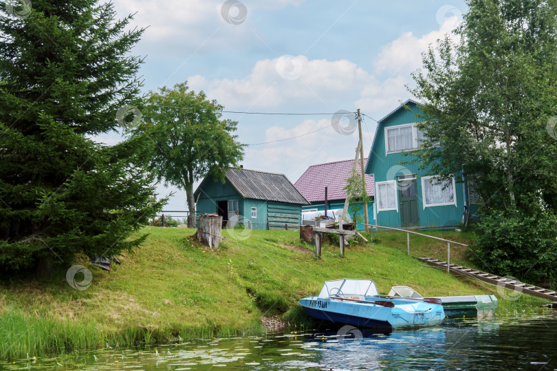 Скачать Дом и лодка на берегу реки. Аккуратная набережная реки. Частная территория у реки. фотосток Ozero