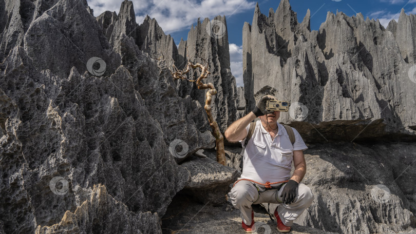 Скачать Мужчина с рюкзаком сидел на корточках среди камней. фотосток Ozero