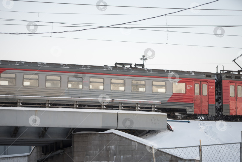 Скачать Россия, Санкт-Петербург, декабрь 2024 года: Электропоезд проезжает по железнодорожному мосту зимним днем фотосток Ozero