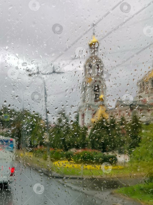 Скачать Вид на православную церковь и городскую улицу в дождливую погоду через стекло, залитое водой фотосток Ozero