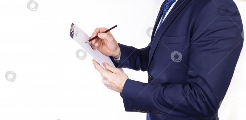 Скачать Бизнесмен в темном костюме с белым листом бумаги и ручкой в руках на белом фоне фотосток Ozero