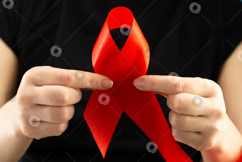 Скачать Концепция здравоохранения и медицины. Осведомленность о СПИДе. Женские руки держат красную ленту для информирования о СПИДе. Всемирный день борьбы со СПИДом фотосток Ozero