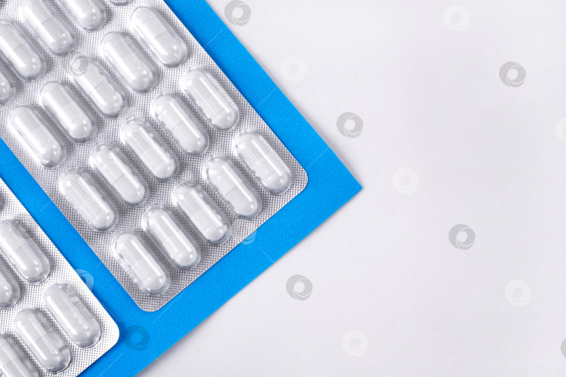 Скачать Таблетки в капсулах в блистерной упаковке на бело-синем фоне. Медицинское и фармацевтическое образование. фотосток Ozero