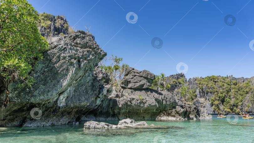 Скачать Живописная тропическая лагуна. По бирюзовой воде плывут туристические каноэ. фотосток Ozero