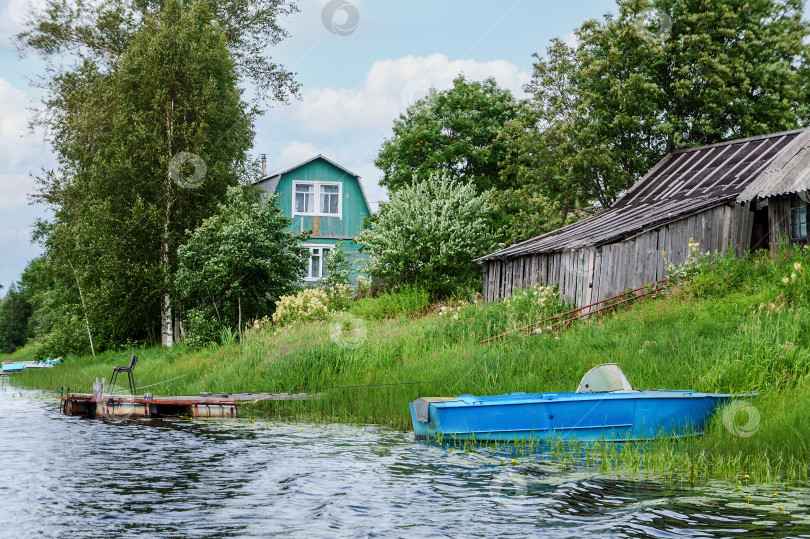 Скачать Дом и лодка на берегу реки. Аккуратная набережная реки. Частная территория у реки. фотосток Ozero