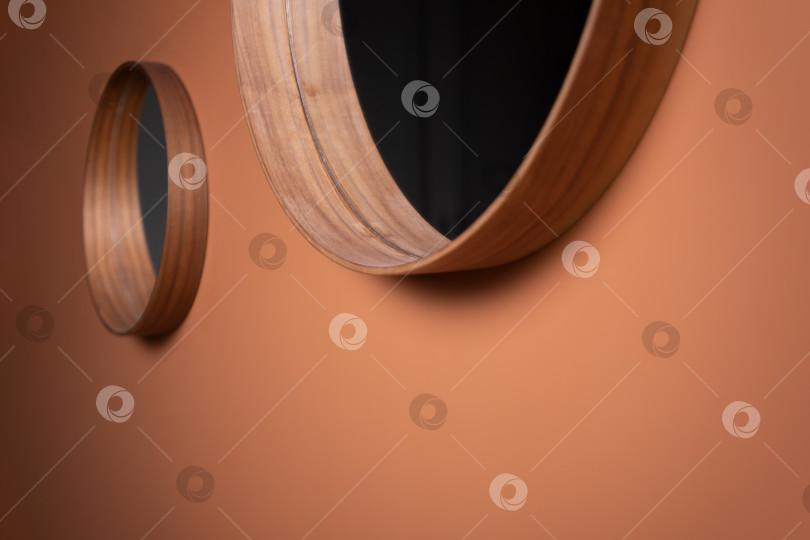 Скачать на оранжевой стене висит круглое декоративное зеркало в деревянной раме фотосток Ozero