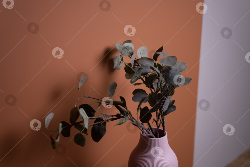Скачать розовая ваза с зеленым растением стоит на коричневом деревянном столе на фоне оранжевой стены фотосток Ozero