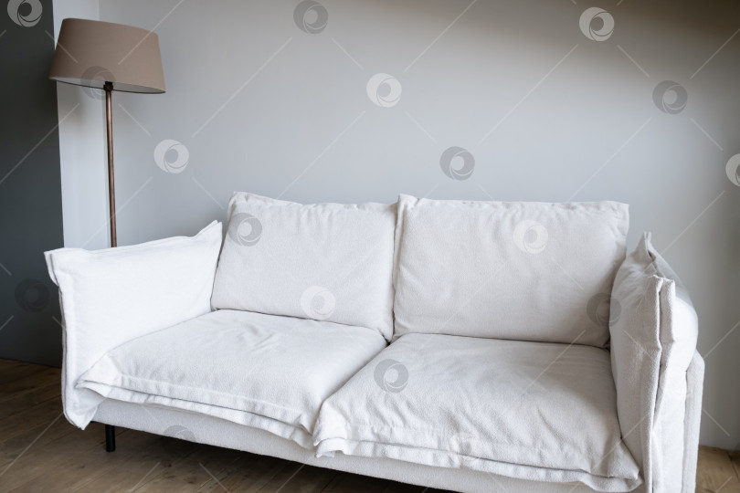 Скачать белый диван у светлой стены, рядом с ним торшер фотосток Ozero