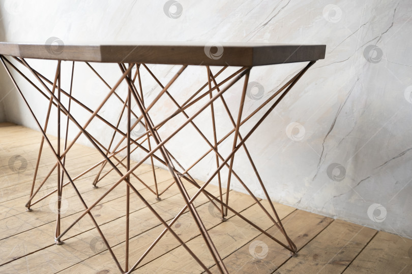 Скачать стол с тонкими золотыми декоративными ножками стоит в комнате с деревянным полом и мраморными стенами фотосток Ozero