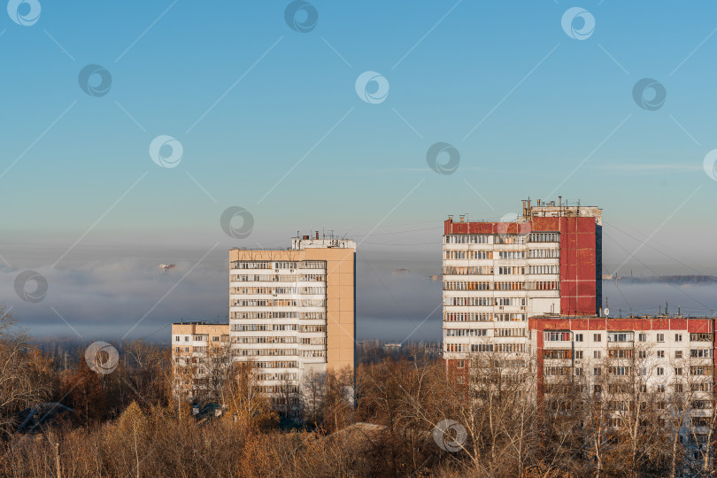 Скачать Многоэтажные дома на фоне тумана на переднем плане деревья без листвы фотосток Ozero