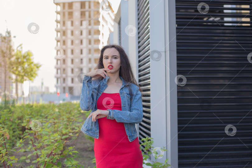 Скачать Молодая девушка в красном платье стоит перед зданием. фотосток Ozero