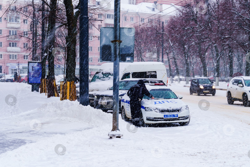 Скачать Инспектор ДПС очищает автомобиль от снега. Воронеж фотосток Ozero