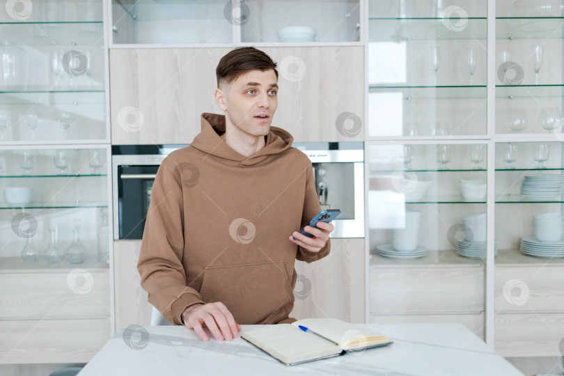 Скачать Мужчина сидит за столом с мобильным телефоном в руке фотосток Ozero