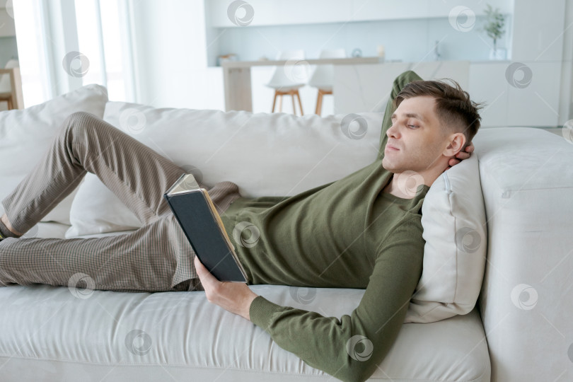 Скачать Мужчина читает книгу на диване фотосток Ozero