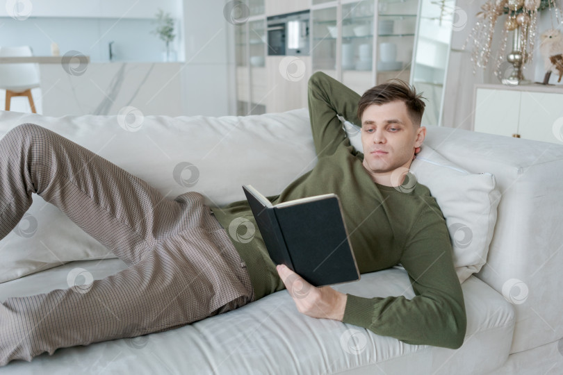 Скачать Мужчина читает книгу на диване фотосток Ozero