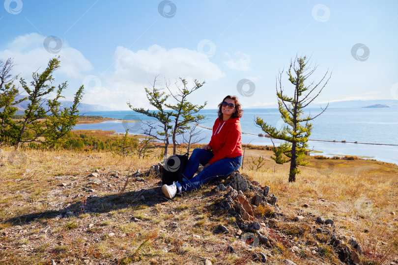 Скачать Женщина с рюкзаком присела отдохнуть на природе фотосток Ozero