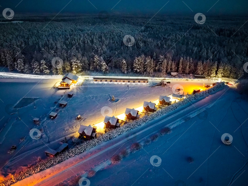 Скачать Домики с вечерней подсветкой возле зимнего леса фотосток Ozero